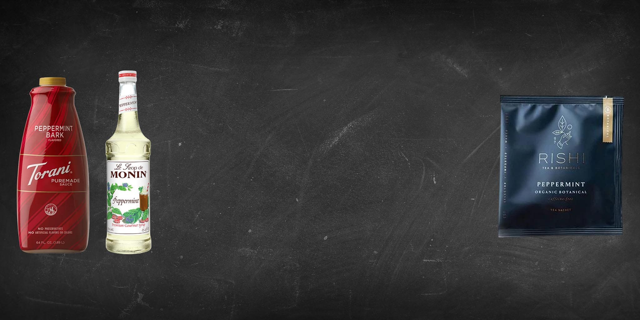 Three bottles of peppermint syrup and a package on a dark background