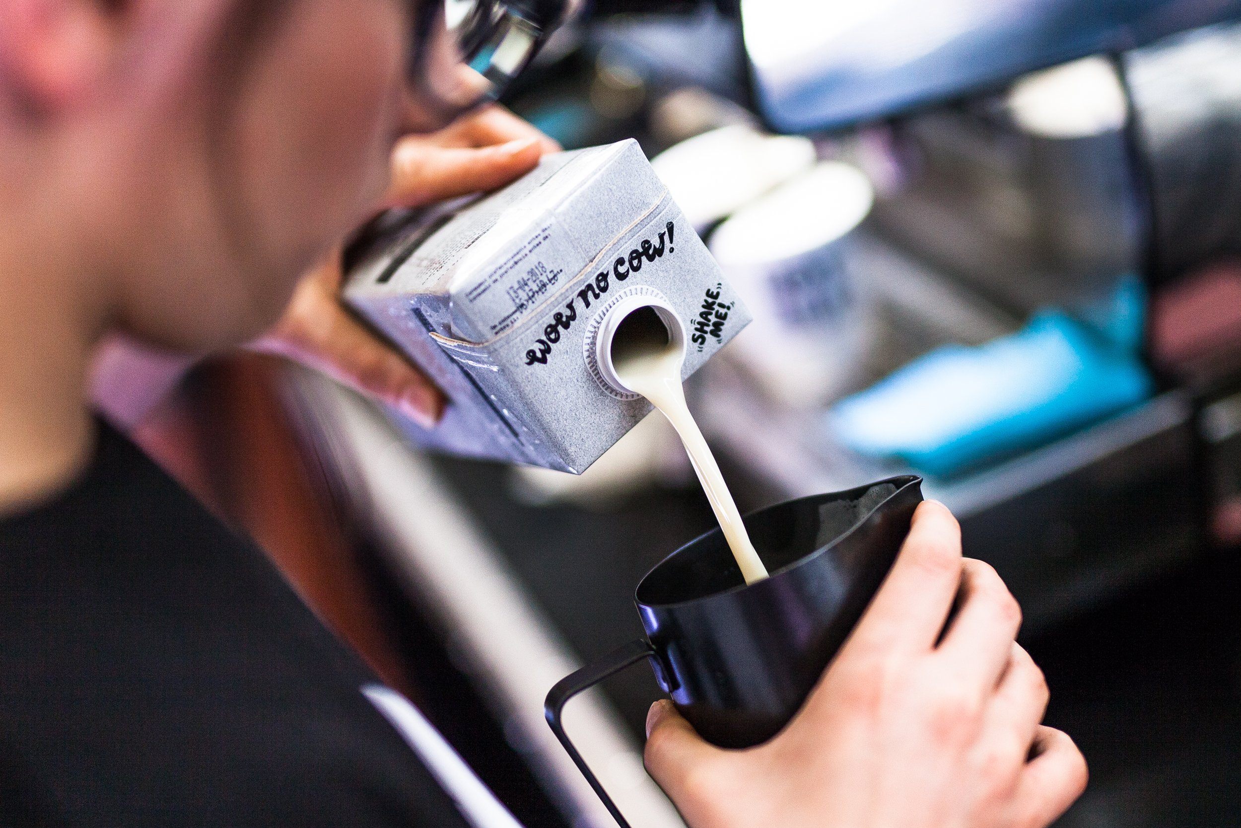 barista pouring oatly barista edition into cup
